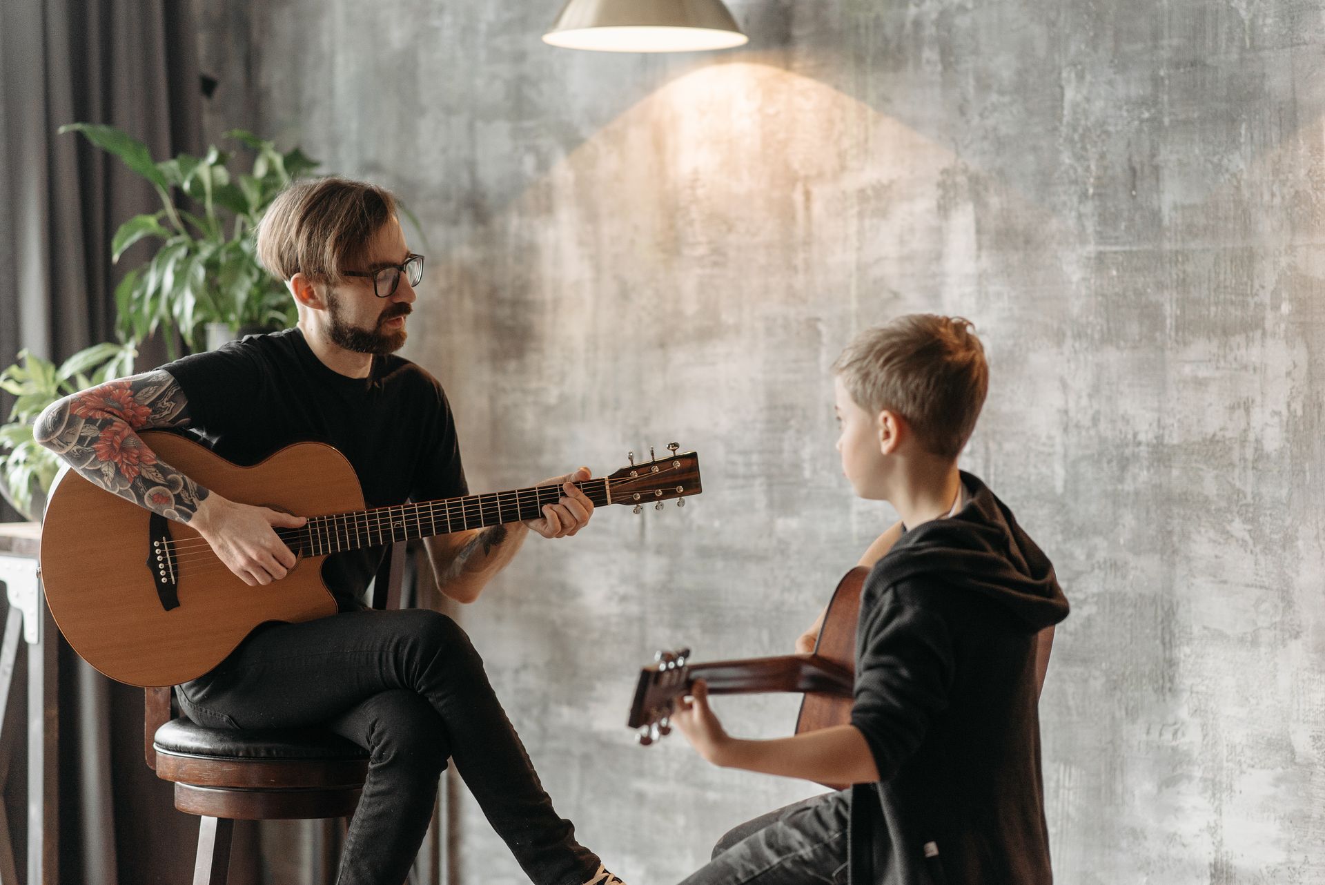 A guitar teacher giving a one-to-one acoustic guitar lesson to a student